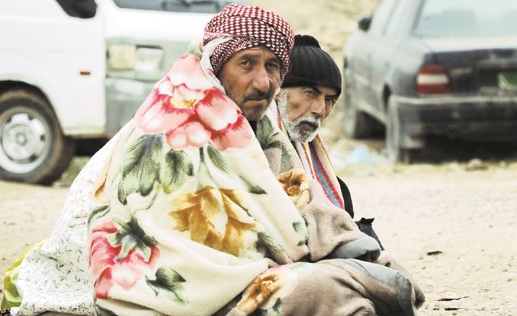 عراقيان نازحان من الموصل يلتحفان بغطاء من البرد القارس قرب احد المعسكرات في اربيل امس الاول( ا.ف.ب) ﻿