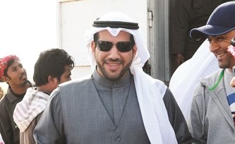 الشيخ عبدالله الأحمد يحمل شتلتين قبل توزيعهما﻿