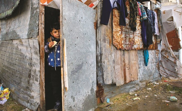 طفل فلسطيني ينظر من باب بيت عائلته امس بالقرب من انقاض مبنى دمر جراء قصف اسرائيل لغزة في 2014 	(أ.ف.پ)﻿