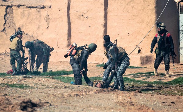 جنود عراقيون يخلون زملاء لهم أصيبوا في هجوم بآلية مفخخة لـ «داعش» جنوب الموصل      				  (أ.ف.پ)