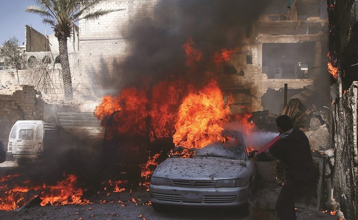 مدني يحاول اطفاء الحريق الذي سببته غارة جوية على مدينة دوما المحاصرة بريف دمشق 	(رويترز )﻿