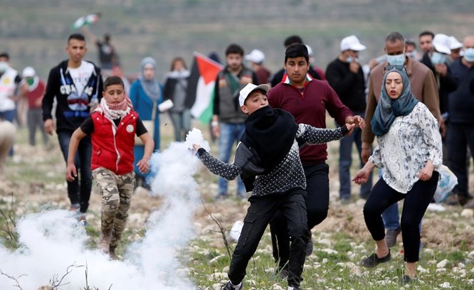 شاب فلسطيني يلقي عبوة غاز مسيل للدموع على جنود الاحتلال خلال اشتباكات في ذكرى يوم الارض بقرية مادوما امس(ا.پ)﻿