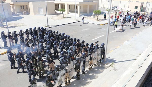 قوات مكافحة الشغب تستعد للسيطرة على أعمال عنف يقوم بها متظاهرون في الجهة المقابلة