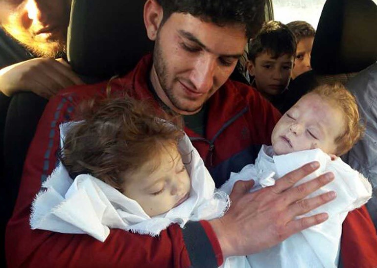 صور مؤلمة.. سوري يحتضن جثماني توأمه بعد مجزرة إدلب