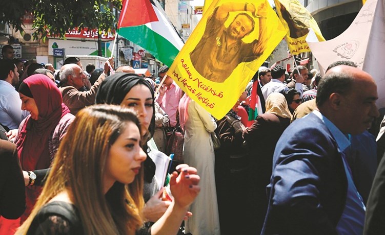 فلسطينيون يرفعون صورا للاسرى في سجون الاحتلال بينهم مروان البرغوثي خلال تظاهرة لاحياء ذكرى يوم الاسير في الضفة امس( ا.ف.ب)﻿