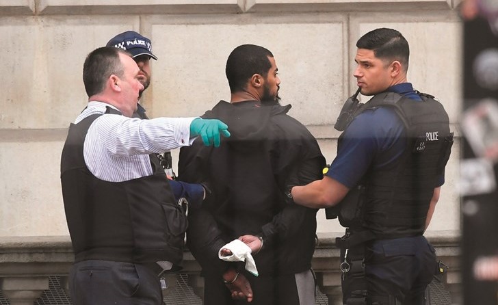 عناصر من الشرطة البريطانية يقتادون الشخص المسلح بعد توقيفه قرب مقر البرلمان (رويترز)﻿