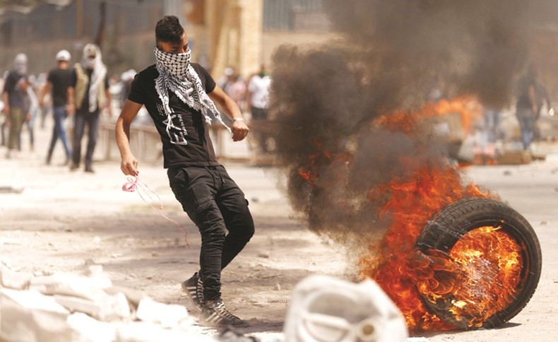 شاب فلسطيني يقذف إطارا مشتعلا باتجاه قوات الاحتلال خلال مواجهات في الضفة الغربية امس الاول	( رويترز) ﻿