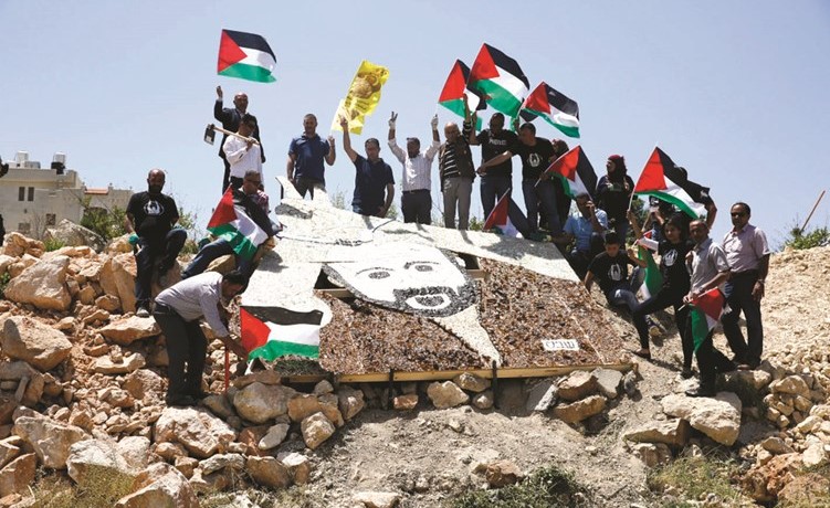 فلسطينيون يتحلقون حول صورة رمزية لمروان البرغوثي ويرفعون العلم الوطني خلال تظاهرة للتضامن مع الاسرى في رام الله امس (أ.پ) ﻿