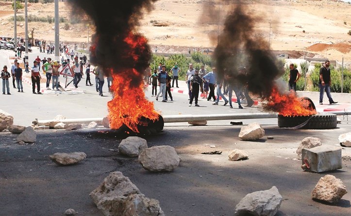 نيران تتصاعد من اطارات محترقة فيما يلقي فلسطينيون بالحجارة خلال اشتباكات مع قوات الاحتلال بالضفة امس(أ.ف.پ)﻿