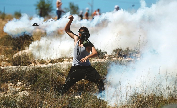 شاب فلسطيني يعيد قذف قنبلة مسيلة للدموع باتجاه قوات الاحتلال خلال مواجهات في رام الله امس( ا.ف.پ)﻿