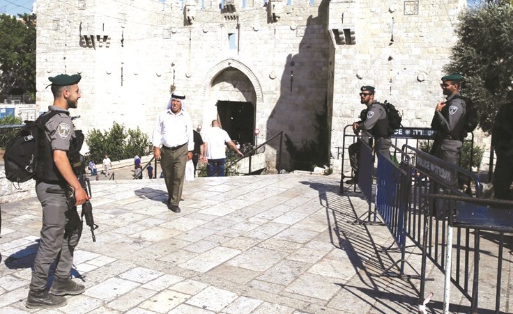 فلسطينيون يمرون من بوابة دمشق بالقرب من عناصر من قوات الاحتلال في القدس القديمة	(أ.ف.پ)﻿