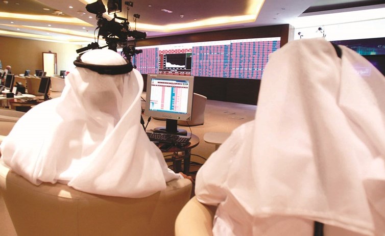 متداولون يراقبون شاشات عرض الأسهم في بورصة قطر بالدوحة أمس (رويترز)﻿