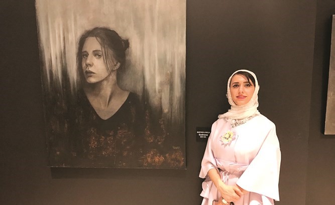 مريم الملا بجانب احدى لوحاتها﻿