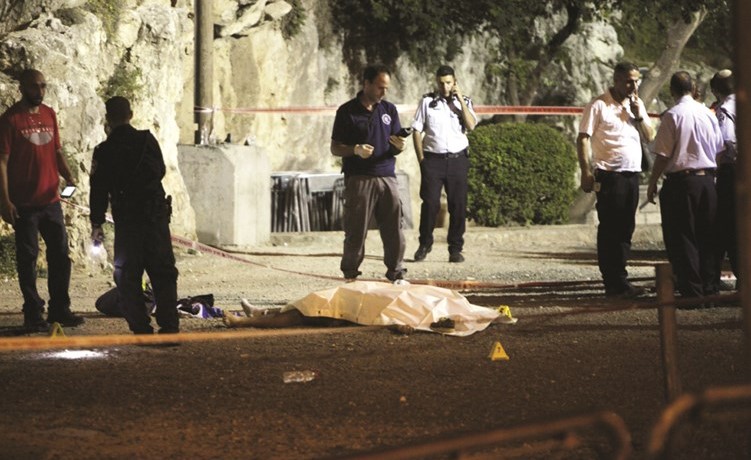 عناصر من شرطة الاحتلال يفحصون موقع الحادث حيث تبدو جثة احد منفذيه الفلسطينيين الثلاثة في القدس امس الاول	(ا.پ)﻿