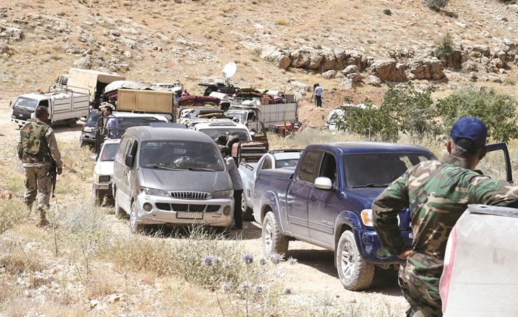 عناصر من حزب الله تراقب قافلة اللاجئين المغادرة لبلدة عرسال	(رويترز) ﻿