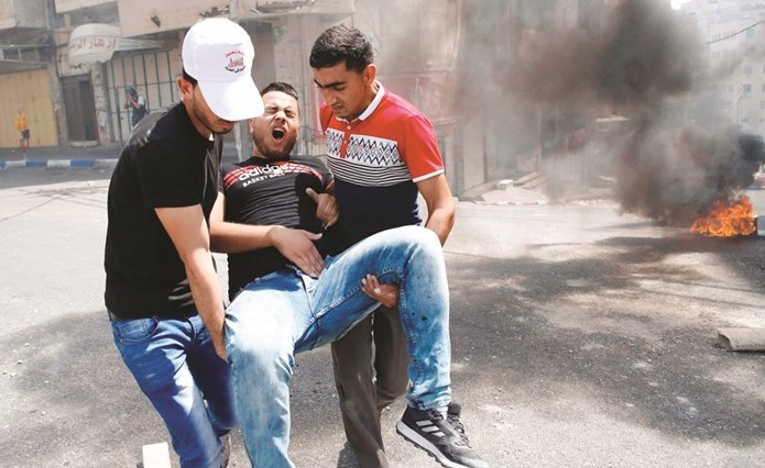 فلسطينيان يحملان احد المصابين في مواجهات بالخليل امس	(أ.ف.پ)﻿