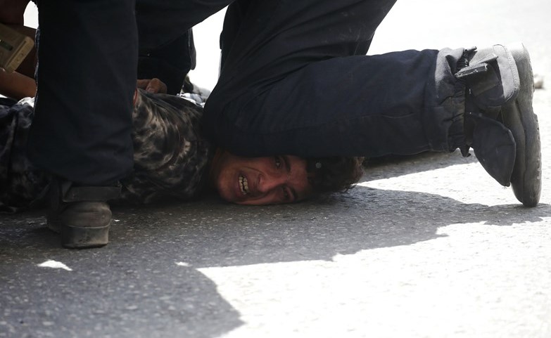 عنصر من شرطة الاحتلال يبطش باحد المتظاهرين الفلسطينيين خلال مواجهات في الخليل امس( أ.ف.پ)﻿