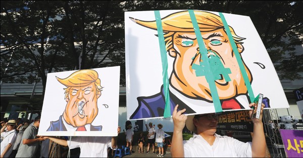 رسم كاريكاتوري للرئيس دونالد ترامب رفعه متظاهرون كوريون جنوبيون احتجاجا على نشر منظومة صواريخ «ثاد» الاميركية         (أ.پ)