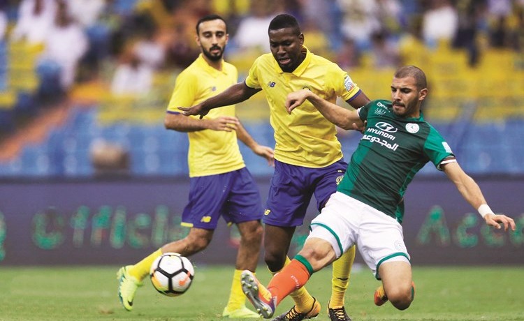 مدافع الاتفاق فهد الهاجري يبعد الكرة قبل لاعب النصر ﻿