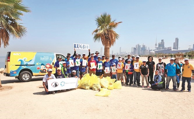 عدد من المتطوعين أثناء تنظيف شاطئ السلام في منطقة الشويخ ﻿