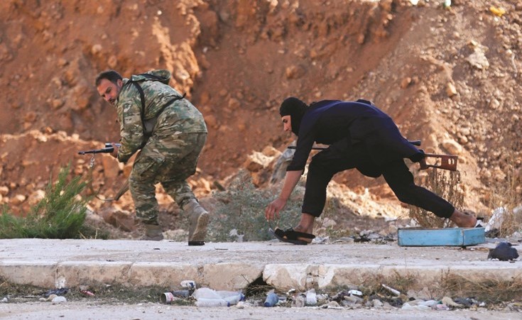 مقاتلون من الجيش الحر يحتمون خلال معركة في مدينة تادف بريف حلب -(رويترز) ﻿