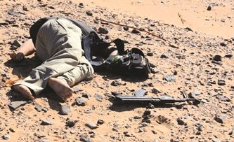 جثة أحد الارهابيين عقب انتهاء المواجهة الأمنية في طريق الخارجة وفي الاطار الأسلحة والأحزمة الناسفة المضبوطة ﻿