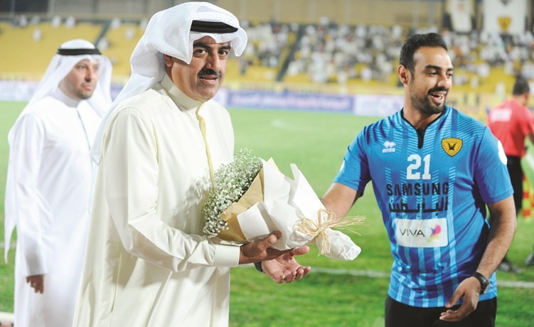 عبدالعزيز المرزوق يتلقى بوكيه ورد من لاعب القادسية المعتزل علي جواد على هامش المباراة	(هاني الشمري) ﻿