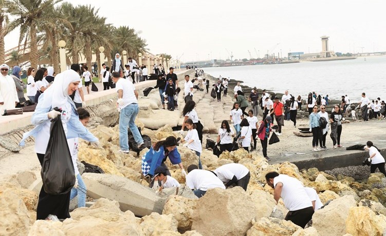 طلاب المدارس والشباب المتطوعون خلال قيامهم بجمع المخلفات من على الشاطئ وبين الصخور﻿