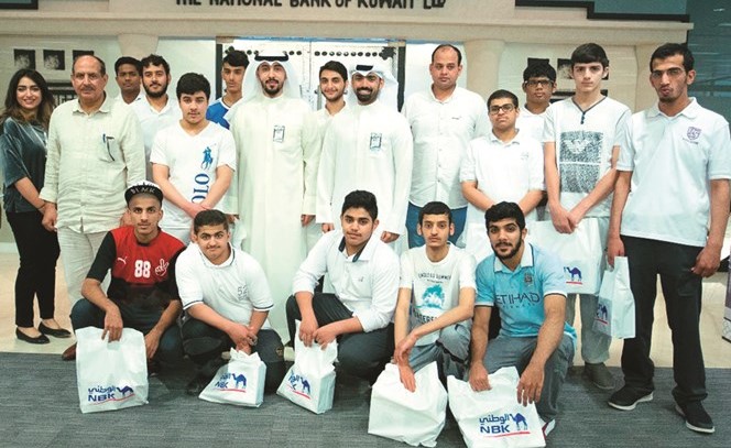 مسؤولون من إدارة العلاقات العامة في البنك مع طلبة مدرسة الأمل المشتركة﻿