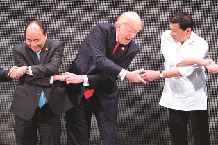 الرئيس الأميركي يشبك يديه مع نظيره الفلبيني (يسار) في ختام اجتماعات آسيان في مانيلا امس( ا.ف.پ)