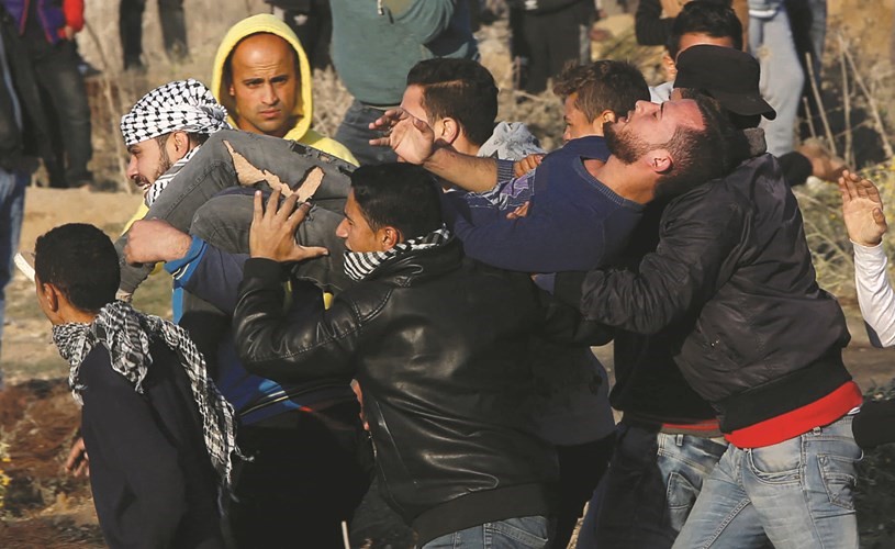 فلسطينيون يساعدون مصابا في غزة 	(أ.پ)﻿