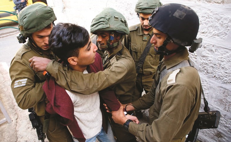 عناصر من قوات الاحتلال يعتقلون صبيا فلسطينيا عقب مواجهات في مدينة الخليل امس 	(أ.ف.پ)﻿