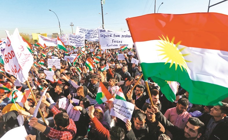 متظاهرون أكراد يلوحون بعلمهم الوطني ويرفعون لافتات منددة برئيس الوزراء العراقي خلال مسيرة احتجاجية في اربيل امس(أ.ف.پ)﻿