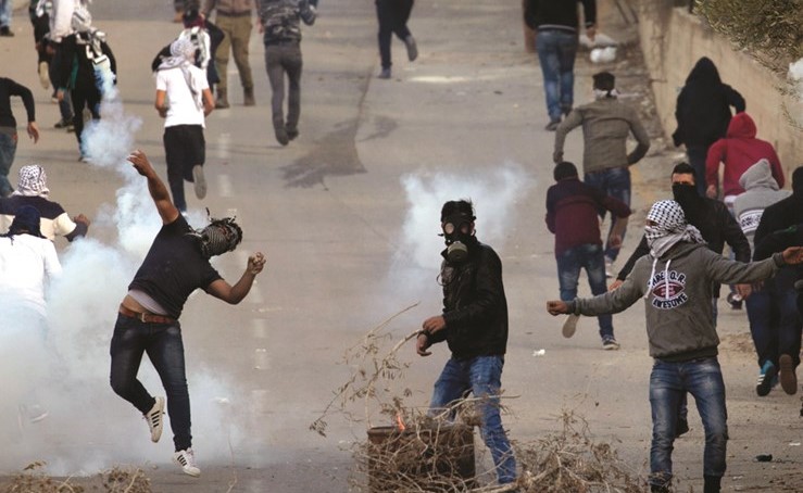 فلسطينيون يلقون الحجارة على قوات الاحتلال خلال اشتباكات في «الناقورة» بالضفة امس	(أ.ف.پ) 