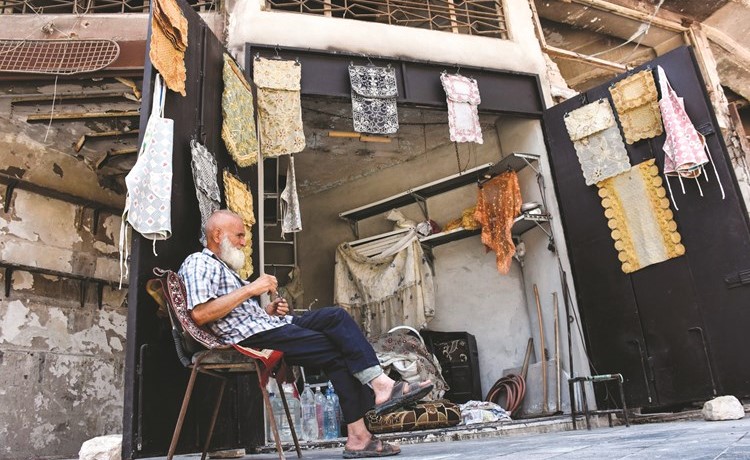 محمد شواش يجلس أمام محله وحيدا بين الركام في أسواق حلب(أ.ف.پ)﻿
