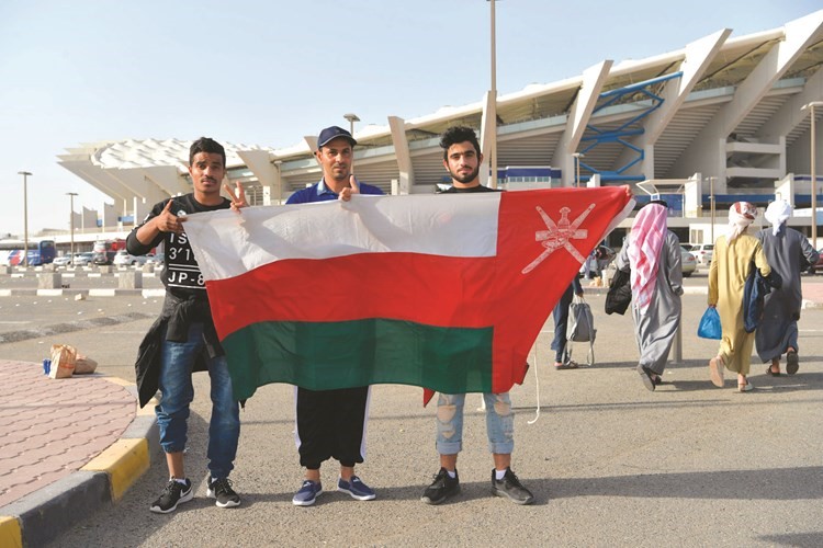 ثلاثة عمانيين يحملون علم بلادهم﻿