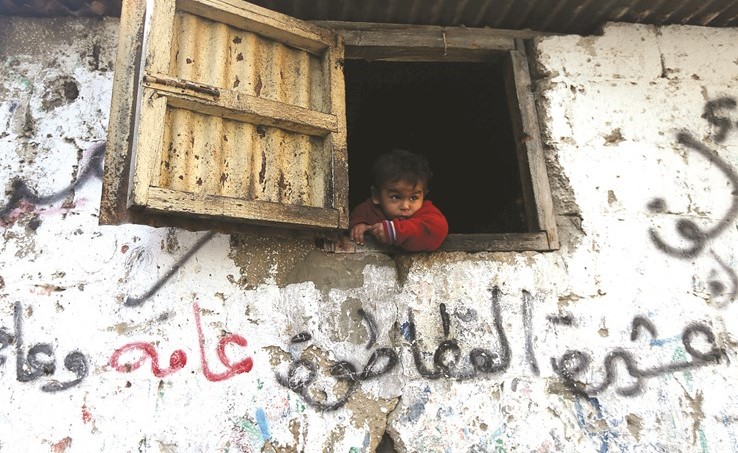 طفل فلسطيني يطل من نافذة بيته في معسكر خان يونس للاجئين بغزة امس	(رويترز) ﻿
