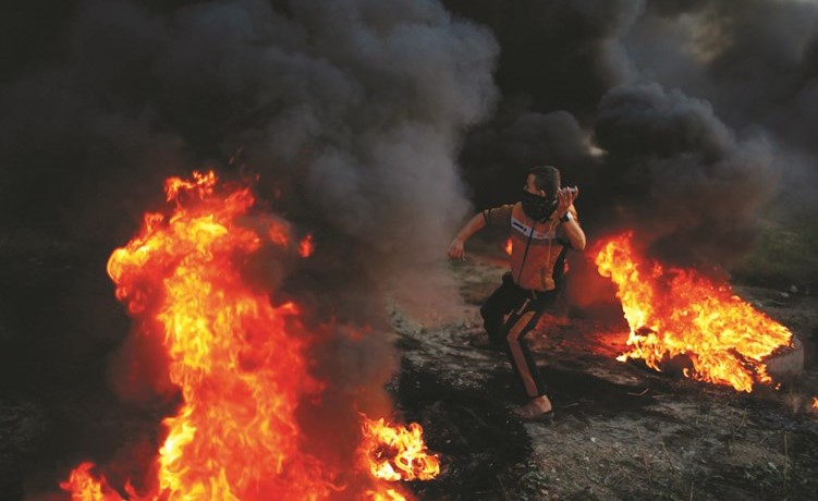 فتى فلسطيني يلقي الحجارة باتجاه قوات الاحتلال خلال مواجهات عنيفة على حدود غزة امس الاول ( رويترز) ﻿