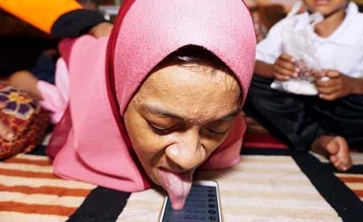معاقة تستخدم لسانها لترويج عملها على هاتفها الذكي