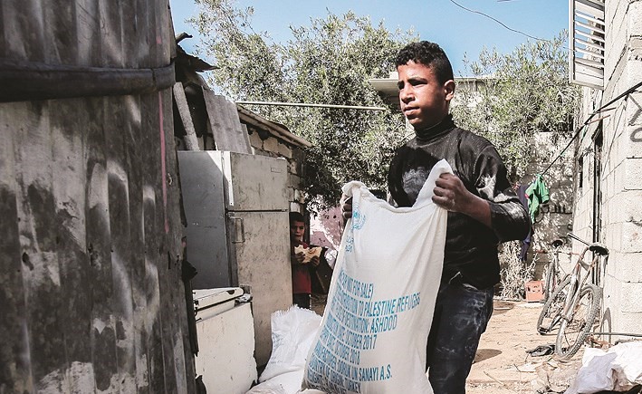 شاب فلسطيني يحمل الدقيق الذي حصل عليه من اونروا الى عائلته في معسكر للاجئين جنوب غزة امس الاول	(أ.ف.پ)﻿