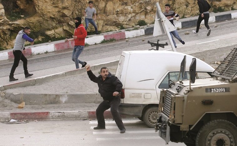 فلسطينيون يلقون الحجارة على قوات الاحتلال خلال مواجهات بالضفة امس الاول	(ا.ف.پ)﻿