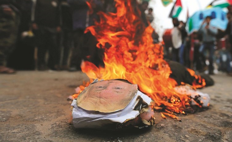 فلسطينيون يحرقون صورة للرئيس الأميركي دونالد ترامب خلال احتجاج على تخفيض المساعدات الأميركية في غزة امس- (رويترز)﻿