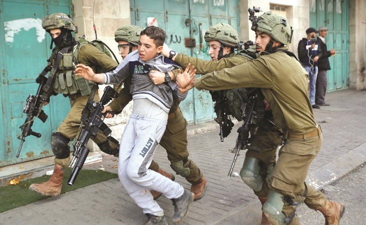 عناصر من قوات الاحتلال خلال اعتقالهم فتى فلسطينيا في الخليل امس					(رويترز) ﻿