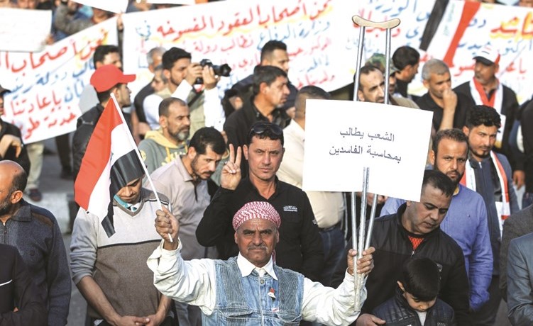 عراقيون يرفعون لافتات مناهضة للفساد خلال تظاهرة في ساحة التحرير ببغداد       ( ا.ف.ب)﻿