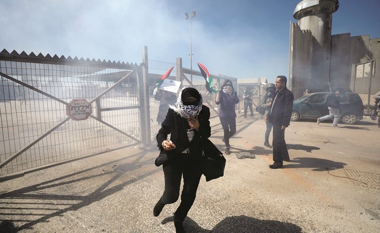  فلسطينيون يحتمون من الغاز المسيل للدموع الذي اطلقه الاحتلال ضد تظاهرة في رام الله امس	(رويترز) ﻿