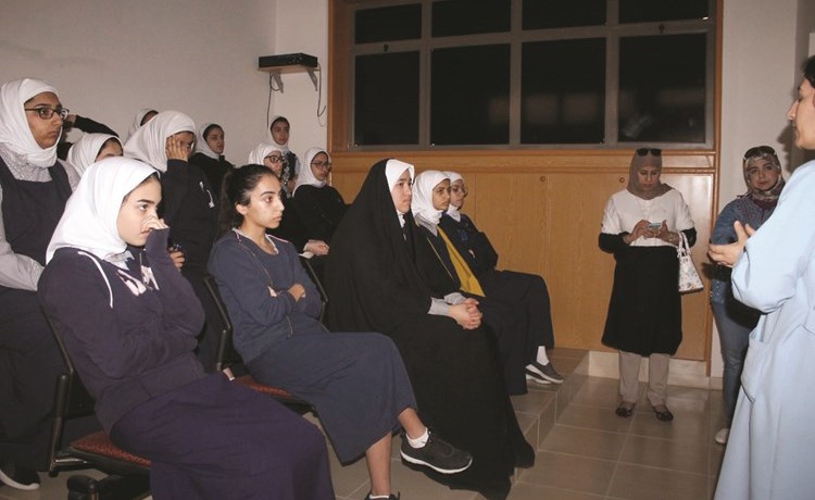 الطالبات يستمعن إلى شرح عن دور المركز الإنساني ﻿