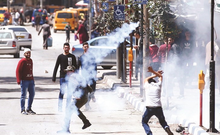 القنابل المسيلة للدموع التي اطلقها الاحتلال تصيب فلسطينيين خلال مواجهات في مدينة الخليل بالضفة امس- (أ.ف.پ)﻿