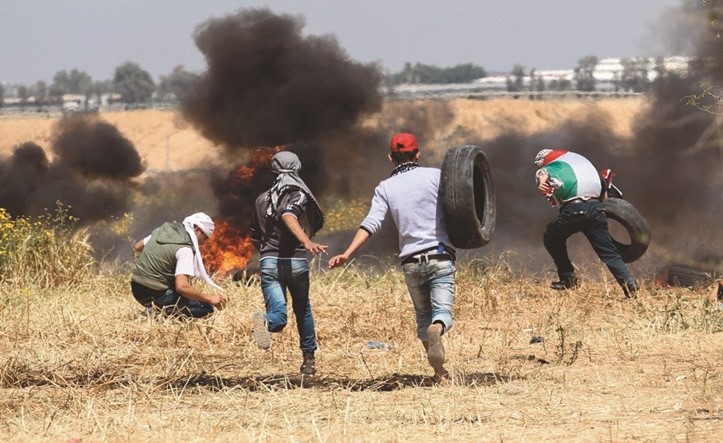 فلسطينيون خلال مواجهات مع الاحتلال قرب السياج الحدودي في غزة امس	(ا.ف.پ)﻿