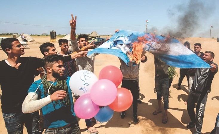 فلسطينيون يحرقون العلم الاسرائيلي قرب حدود قطاع غزة امس ضمن مسيرات العودة الكبرى-(أ.ف.پ) ﻿