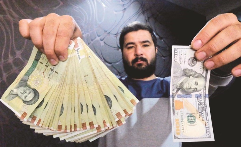 موظف تبديل عملات يعرض الدولار الاميركي مقابل ما يساويه من الريالات الايرانية	(رويترز)﻿